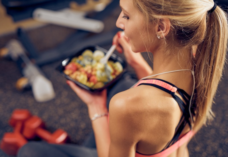 Mujer comiendo un bol saludable después de entrenar en el gimnasio tras su entrenamiento con el Método Bilbo