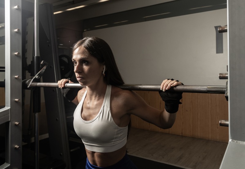 Mujer entrenando fuerza con remo con barra para espalda gracias al Metodo Bilbo